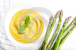 Fresh green asparagus cream soup on white wooden background