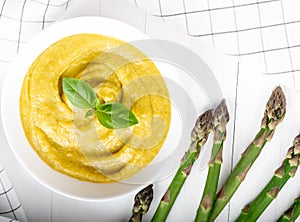 Fresh green asparagus cream soup on white wooden background