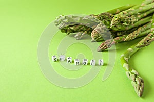 Fresh green asparagus on green background with copy space and cube letters