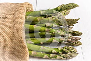 Fresh Green Asparagus in Juta Bag on White Wooden Table