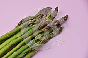 Fresh green asparagus on a pink background, close-up