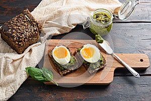 Fresh Green basil pesto in glass jar homemade on old rustic wood eggs panini bread with pesto and hot sriracha sauce italian