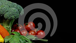 Fresh green broccoli cherry tomatoes, spinach, bell peppers rotating on a black background. Shopping, healthy eating