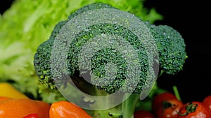 Fresh green broccoli and other vegetables rotating on a black background. Shopping, healthy eating concept.
