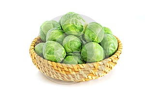 Fresh green brussel sprouts vegetable in a basket on white background