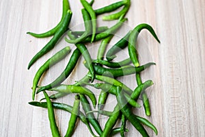 Fresh Green chili pepper on plain wooden table, green essential vegetables for all essential foods, view of unpeeled vegetables