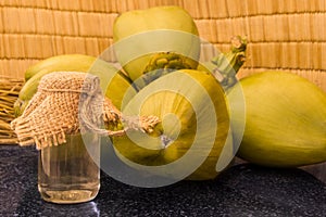 Fresh green coconuts branch and coconut oil in a glass on black granite.