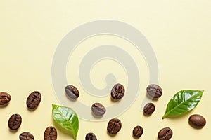 Fresh green coffee leaves and beans on light yellow background, flat lay. Space for