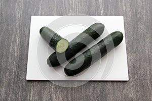 Fresh, green cucumbers on a chopping board with knife are prepared for a nutritious salad or juice on a kitchen table