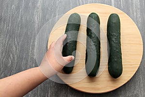 Fresh, green cucumbers on a chopping board with knife are prepared for a nutritious salad or juice on a kitchen table