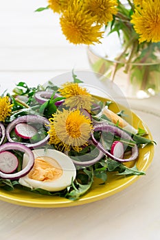 Fresh green dandelion salad on yellow plate