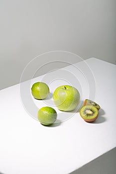 Fresh green fruits on white table, vertical orientation