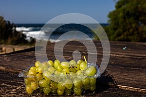 Fresh green grapes in nature against the backdrop of the ocean. Picnic by the water