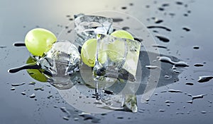 Fresh green grapes with water drops and ice on a gray background