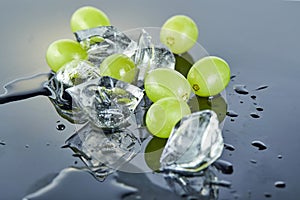 Fresh green grapes with water drops and ice on a gray background