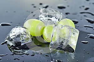 Fresh green grapes with water drops and ice on a gray background