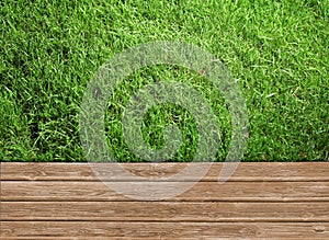 Fresh green grass and wooden surface outdoors, top view