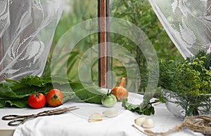 Fresh green herbs, tomatoes, garlic cloves and onion on table indoors