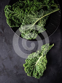 Fresh green kale leaves on dark table. Overhead shot