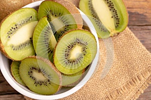 fresh green kiwis slice in the white bowl on the old wooden table
