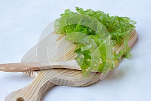 Fresh green leaves of Ulva seaweed, for making salad, on a wooden Board, light background