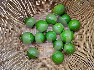 Fresh green limes in the small colorful baskets on the woven bamboo plate. The Thai traditional fresh market