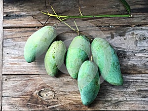 Fresh green mangoes on the wooden table with natural light.