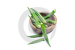 Fresh green okra in a separate wooden bowl on a white background