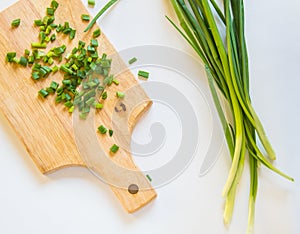 Fresh green onion feathers and cut into pieces on a wooden chopping Board. Top view, flat lay, copying space isolated on white