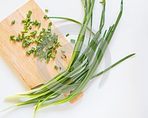 Fresh green onion feathers and cut into pieces on a wooden chopping Board. Top view, flat lay, copying space isolated on white