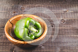 fresh green paprika on a wooden bowl/fresh green paprika on a wooden bowl on a dark background. Copy space