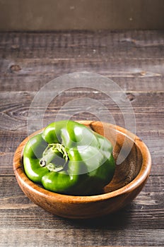 fresh green paprika on a wooden bowl/fresh green paprika on a wooden bowl on a dark background. Selective focus