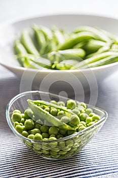 Fresh green pea seeds in bowl on kitchen table
