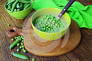 Fresh green pea soup with pea seeds and pea pods around . Selective Focus, Focus on the pea in the middle of the soup