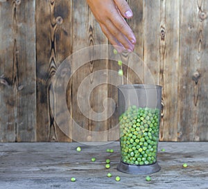Fresh green peas in a Cup on a wooden background. Focus on peas. Copy space.