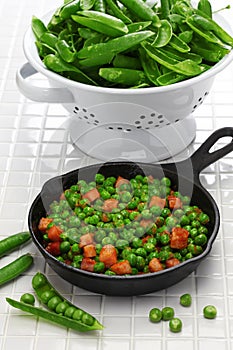 Fresh green peas with ham in skillet photo