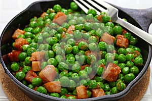 Fresh green peas with ham in skillet photo