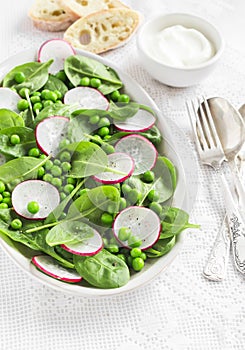 Fresh green peas, spinach and radish salad on a ceramic oval plate