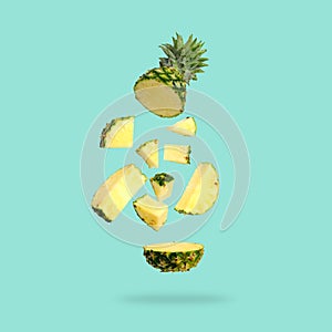 Fresh green pineapple with slice falling in the air isolated on tuquoise photo
