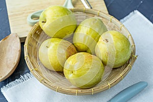 Fresh Green plum or Flavor Grenade Pluot closeup, Green plum in Bamboo basket on wooden table in garden.