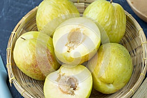 Fresh Green plum or Flavor Grenade Pluot closeup, Green plum in Bamboo basket on wooden table in garden.