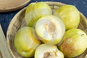 Fresh Green plum or Flavor Grenade Pluot closeup, Green plum in Bamboo basket on wooden table in garden.