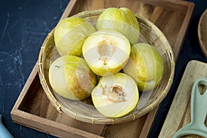 Fresh Green plum or Flavor Grenade Pluot closeup, Green plum in Bamboo basket on wooden table in garden.