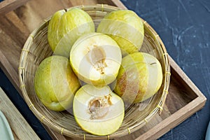 Fresh Green plum or Flavor Grenade Pluot closeup, Green plum in Bamboo basket on wooden table in garden.