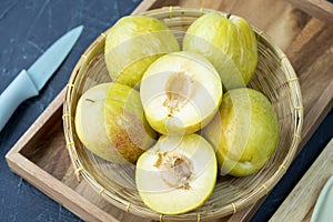 Fresh Green plum or Flavor Grenade Pluot closeup, Green plum in Bamboo basket on wooden table in garden.
