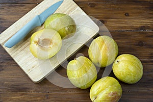 Fresh Green plum or Flavor Grenade Pluot closeup, Green plum in Bamboo basket on wooden table in garden.