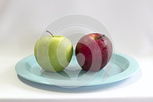 Fresh green & red apple on blue plate.