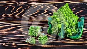 Fresh green Romanesco broccoli on a wooden board, rustic wooden background - healthy or vegetarian food concept. Low-calorie
