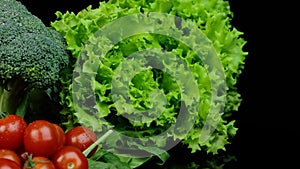 Fresh green salad, broccoli, tomatoes and other vegetables rotating on a checkered background.