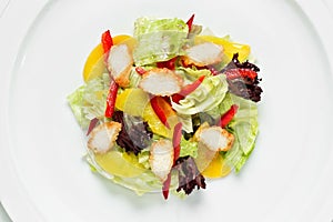 Fresh green salad with chicken nuggets and peach slices top view on a white background